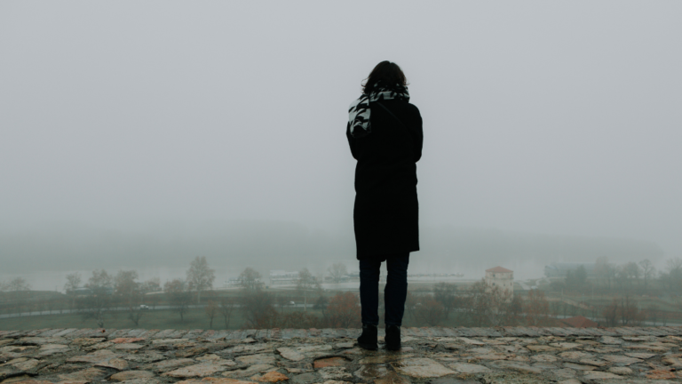 En kvinna tittar ut över ett dimmigt landskap